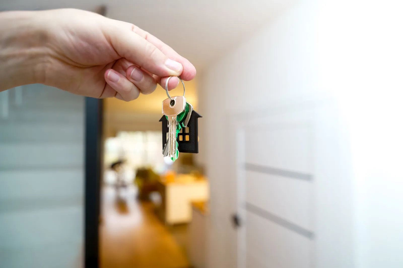 Hand holding a set of house keys inside a home