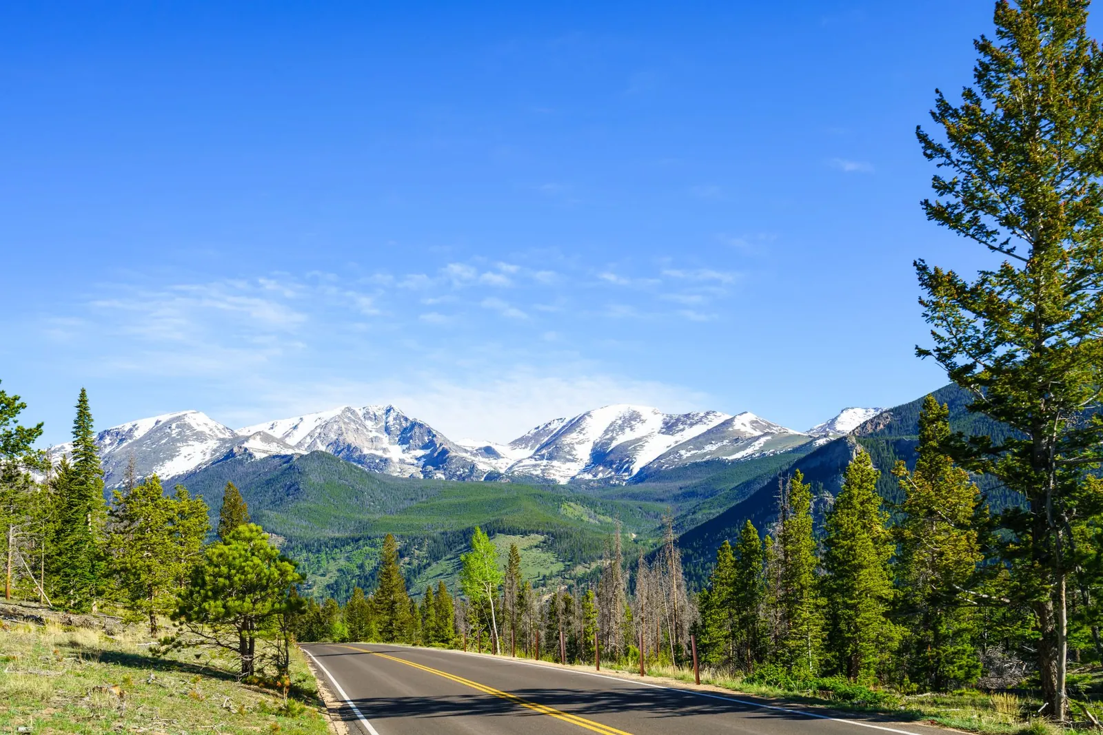 Road through Estes Park, Colorado, with snow-capped Rocky Mountain peaks